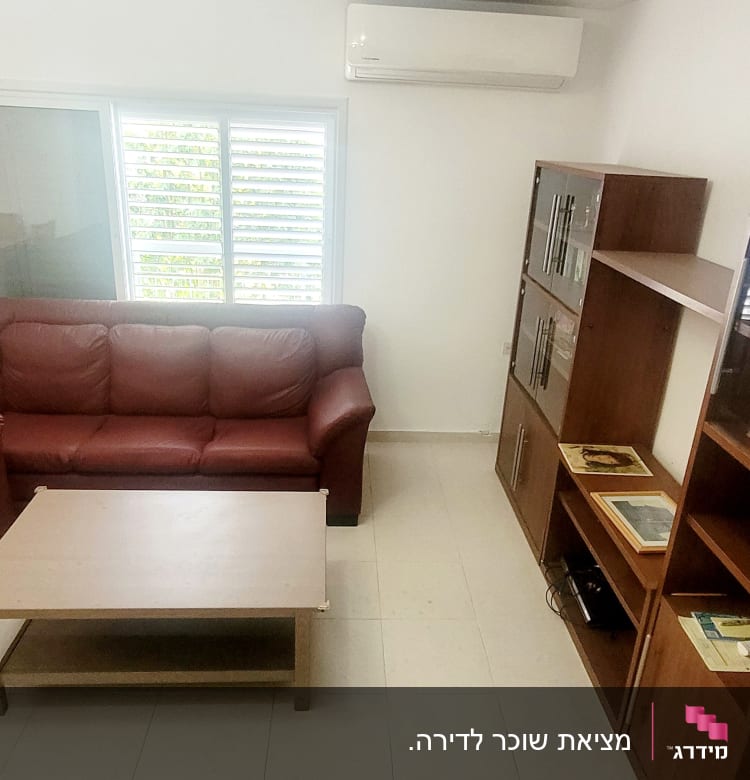 סלון עם ספות עור, שולחן עץ וארון מדפים